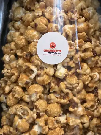 Close-up of caramel popcorn with small dark bits, under a Snakmonster round label